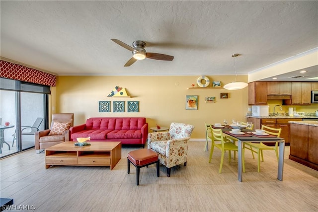 living room with ceiling fan, sink, light hardwood / wood-style floors, and a textured ceiling