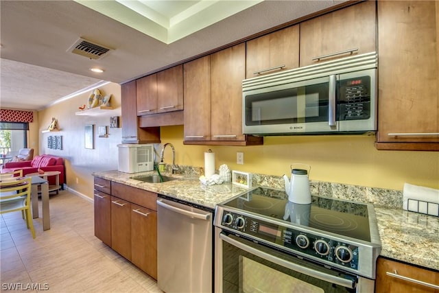 kitchen with light stone counters, sink, and appliances with stainless steel finishes