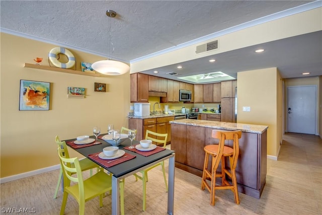 kitchen featuring light stone countertops, crown molding, sink, a kitchen island, and a breakfast bar area