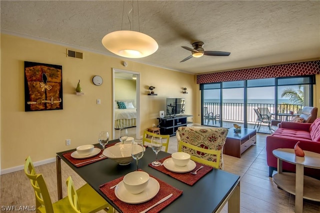 dining room with a textured ceiling, ceiling fan, and crown molding