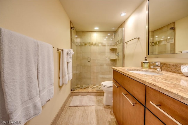 bathroom featuring vanity, toilet, and a shower with door