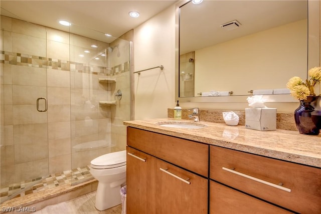 bathroom with vanity, a shower with shower door, and toilet