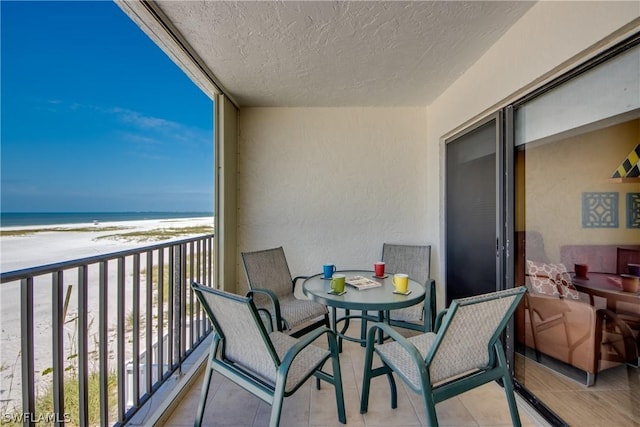 balcony featuring a view of the beach and a water view