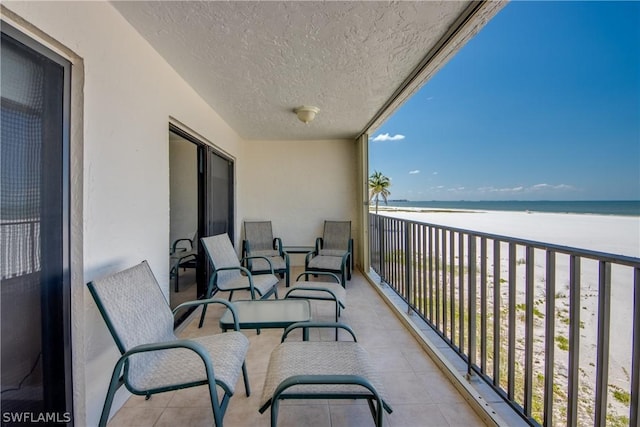 balcony with a water view and a view of the beach