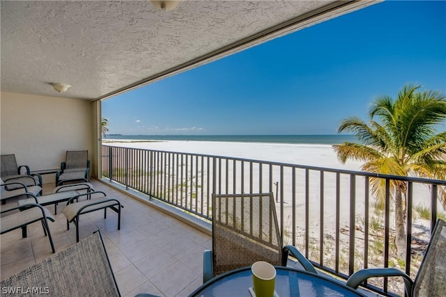 balcony featuring a view of the beach and a water view