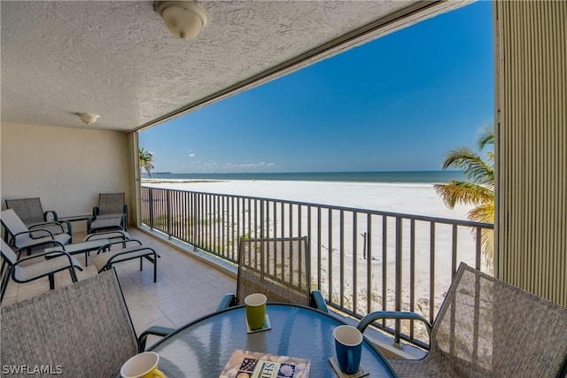 balcony featuring a view of the beach and a water view