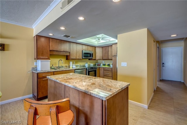 kitchen with appliances with stainless steel finishes, a center island, ceiling fan, and sink