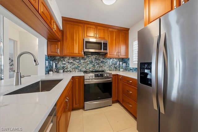 kitchen with light stone countertops, sink, stainless steel appliances, backsplash, and light tile patterned floors