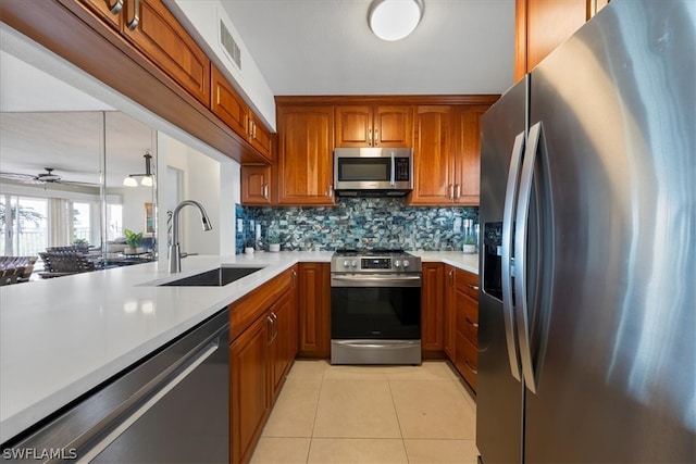 kitchen featuring appliances with stainless steel finishes, backsplash, ceiling fan, sink, and light tile patterned floors