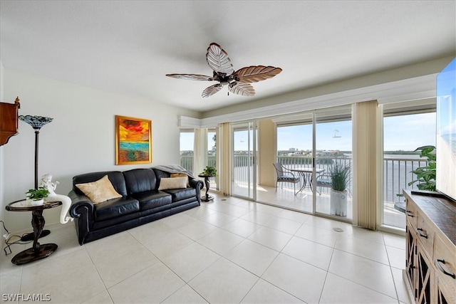 tiled living room featuring ceiling fan and a water view