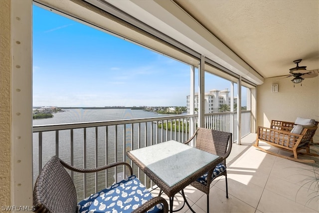 balcony with ceiling fan and a water view