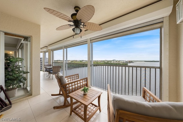 sunroom featuring ceiling fan, a water view, and a wealth of natural light