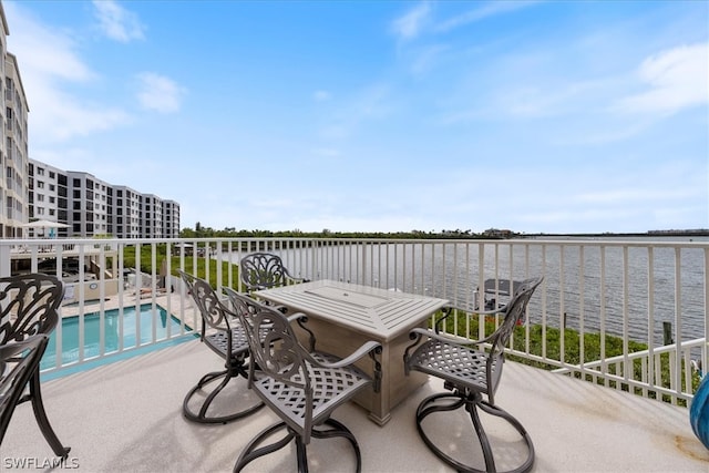 view of patio featuring a fenced in pool, a balcony, and a water view