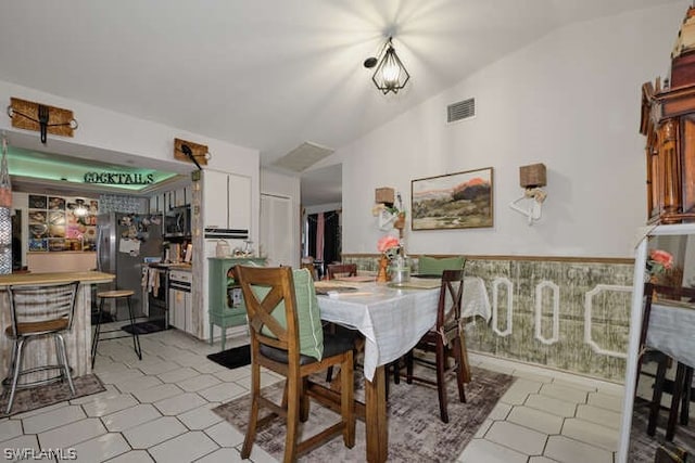 tiled dining room featuring lofted ceiling