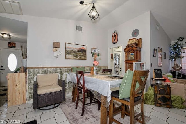 dining area featuring high vaulted ceiling and light tile floors