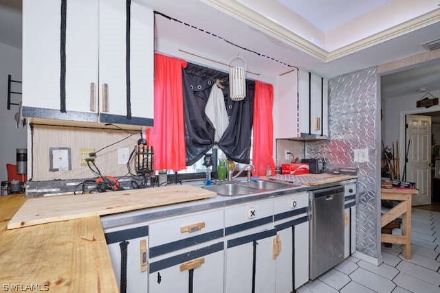 kitchen featuring tasteful backsplash, white cabinetry, sink, light tile floors, and stainless steel dishwasher