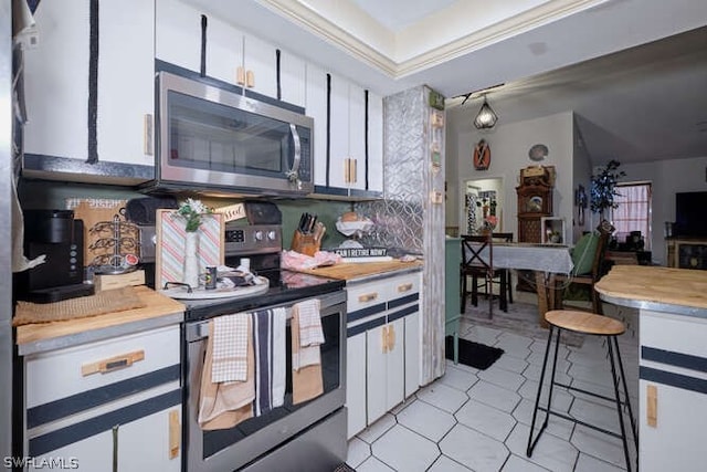 kitchen with tasteful backsplash, stainless steel appliances, light tile floors, and white cabinetry