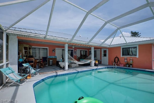 view of pool with glass enclosure and a patio area