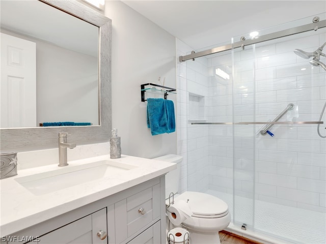 bathroom with toilet, vanity with extensive cabinet space, and a shower with door