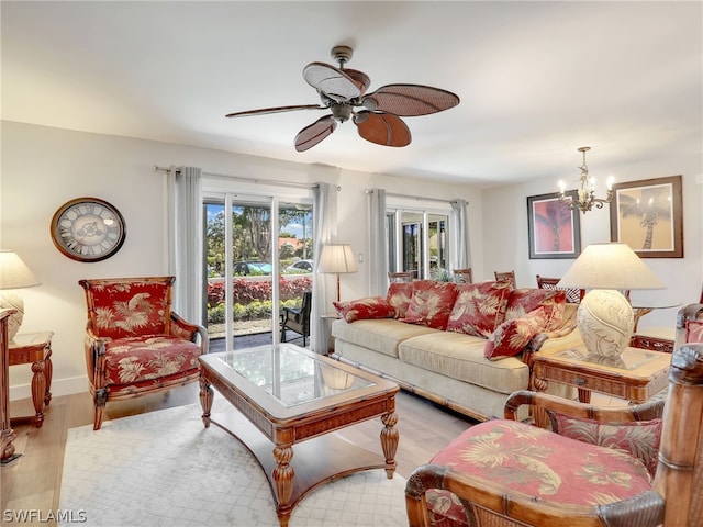 living room featuring ceiling fan with notable chandelier and light wood-type flooring