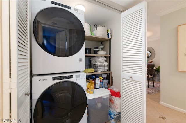 washroom featuring light tile flooring, stacked washing maching and dryer, and crown molding