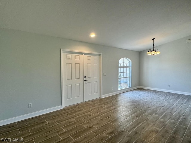 spare room with dark wood-type flooring and a chandelier