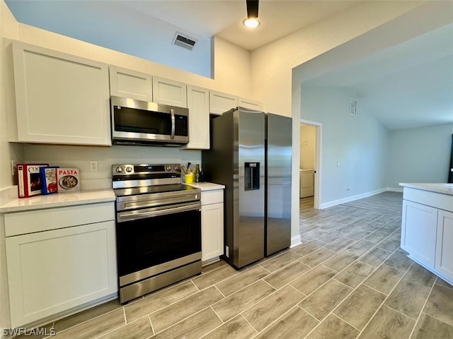 kitchen with stainless steel appliances, white cabinetry, and light hardwood / wood-style floors