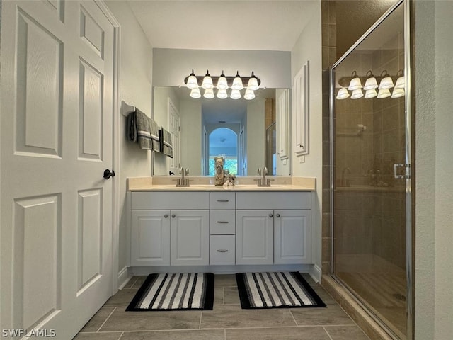 bathroom featuring tile flooring, double sink, vanity with extensive cabinet space, and walk in shower