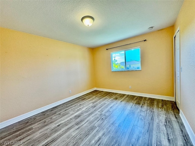 empty room with a textured ceiling and wood-type flooring