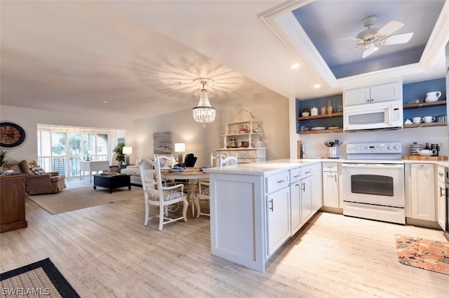 kitchen featuring white appliances, kitchen peninsula, a tray ceiling, decorative light fixtures, and white cabinetry