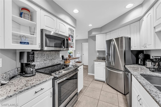 kitchen with light tile flooring, white cabinetry, stainless steel appliances, light stone counters, and tasteful backsplash