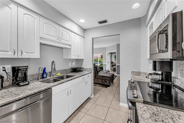 kitchen featuring light stone countertops, stainless steel appliances, white cabinets, sink, and light tile floors