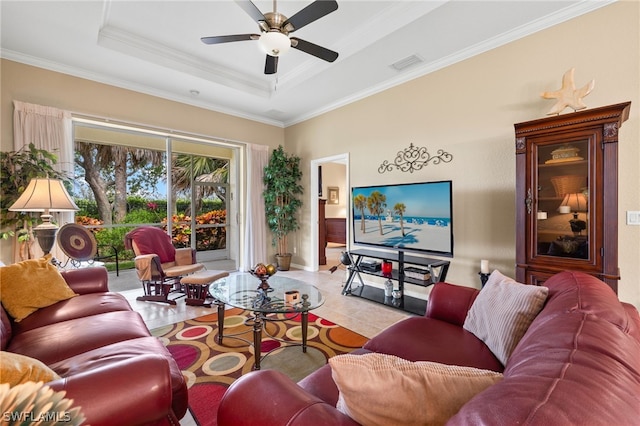 living room featuring ceiling fan, ornamental molding, light tile floors, and a raised ceiling