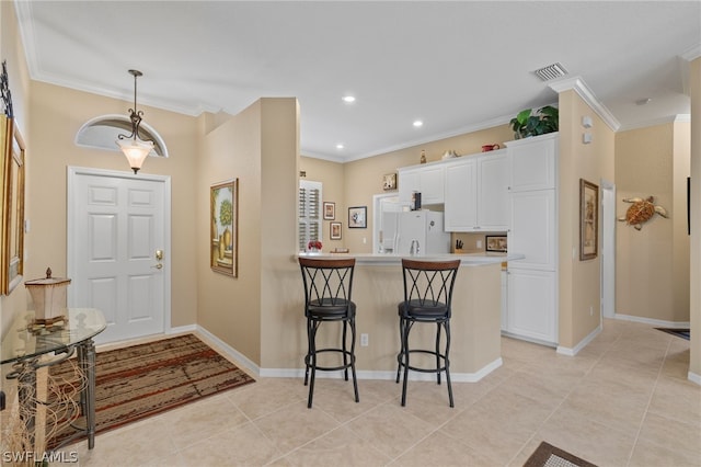 interior space featuring a kitchen bar, light tile floors, decorative light fixtures, white refrigerator, and white cabinets