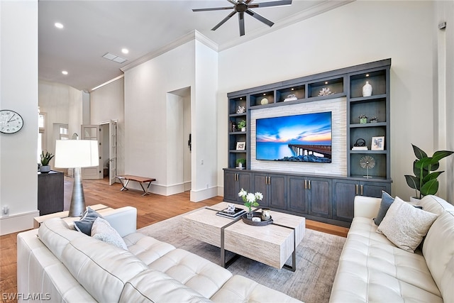 living room with ceiling fan, crown molding, light hardwood / wood-style flooring, and built in shelves