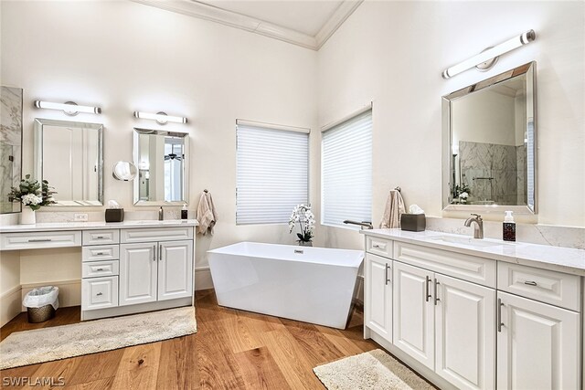 bathroom featuring a bathtub, crown molding, hardwood / wood-style flooring, and vanity with extensive cabinet space