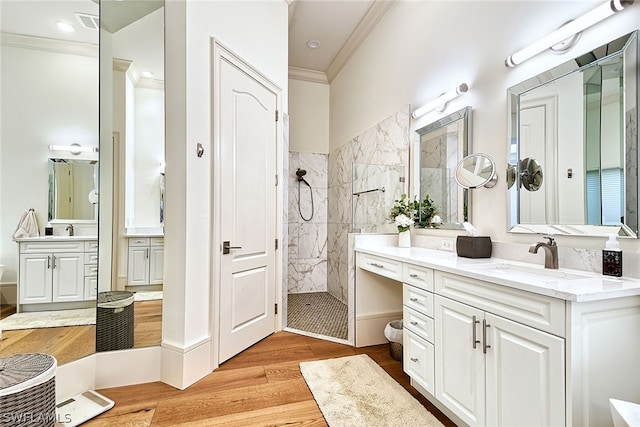 bathroom featuring hardwood / wood-style flooring, crown molding, tiled shower, and vanity