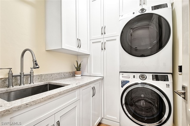 clothes washing area with sink, cabinets, and stacked washer and dryer