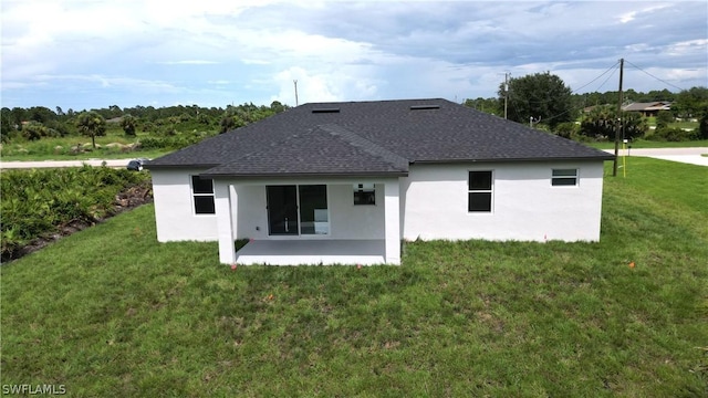 rear view of property featuring a patio, a shingled roof, a lawn, and stucco siding