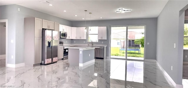 kitchen with marble finish floor, light countertops, appliances with stainless steel finishes, a sink, and a kitchen island