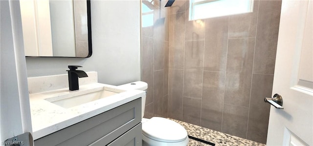 full bath featuring tiled shower, vanity, and toilet