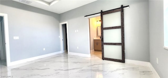 spare room with marble finish floor, a barn door, visible vents, and baseboards