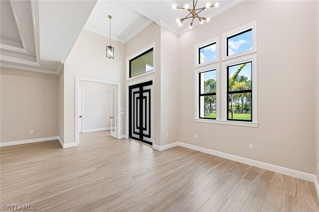 foyer entrance featuring a notable chandelier, light hardwood / wood-style floors, and crown molding