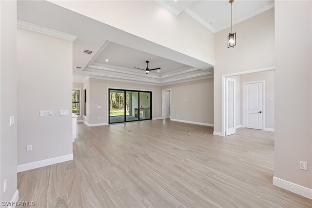 unfurnished living room with ceiling fan, a tray ceiling, light hardwood / wood-style floors, and crown molding