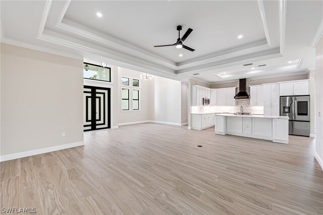 unfurnished living room with sink, light wood-type flooring, and a raised ceiling