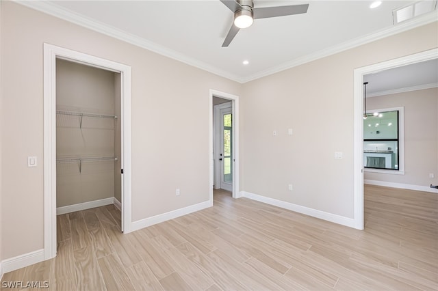 unfurnished bedroom featuring ceiling fan, a closet, a spacious closet, and crown molding