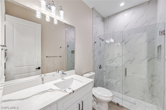 bathroom featuring a shower with door, hardwood / wood-style floors, toilet, and vanity with extensive cabinet space