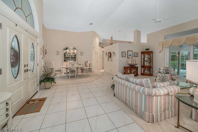 living area featuring light tile patterned floors, ceiling fan with notable chandelier, and a towering ceiling