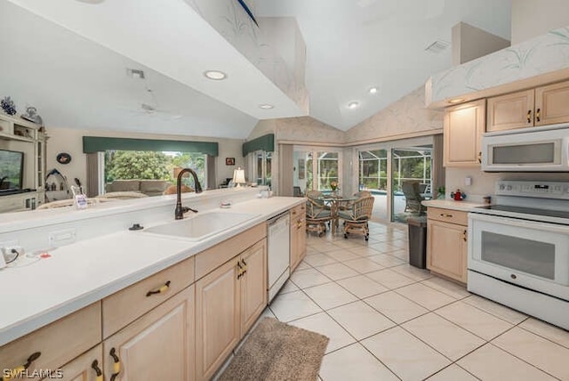 kitchen featuring white appliances, lofted ceiling, light countertops, light brown cabinetry, and a sink