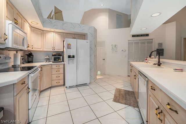 kitchen featuring white appliances, light brown cabinets, light countertops, and a sink